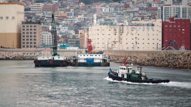 Tugboats Operating Near Densely Packed Coatal Cityscape