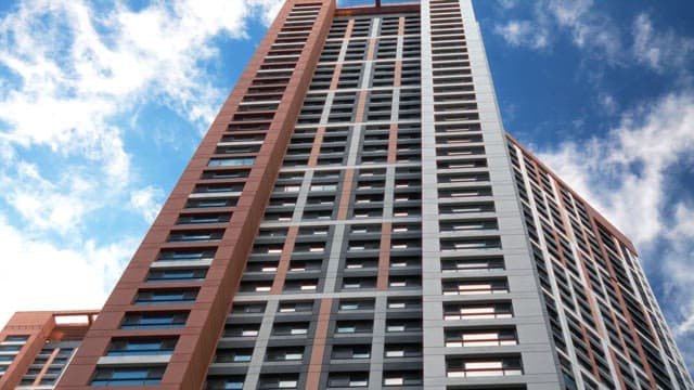 High-rise building rising up to the blue sky with white clouds floating by
