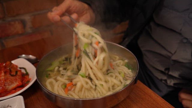 Bowl of steaming kalguksu with kimchi
