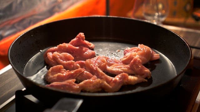 Raw meat placed on a heated frying pan with oil