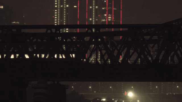 Night view of a bridge with a passing subway and illuminated skyscrapers in the background