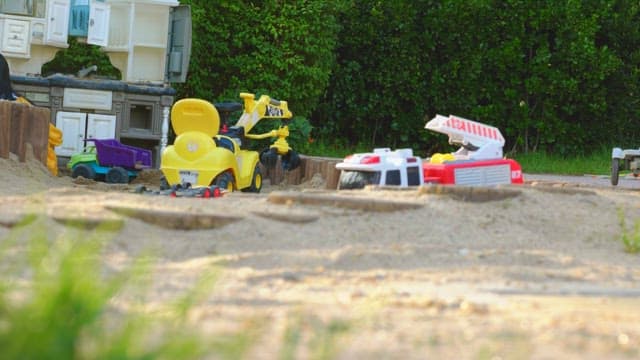 Toys scattered in a sandbox near the backyard garden