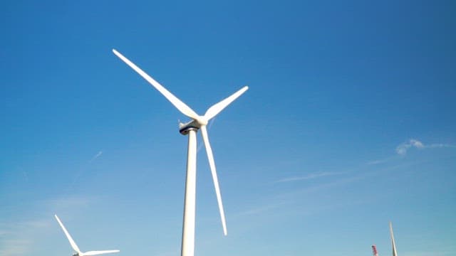 White wind turbines spinning against a clear blue sky