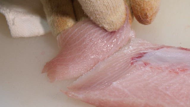 Slicing fresh yellow tail on a cutting board