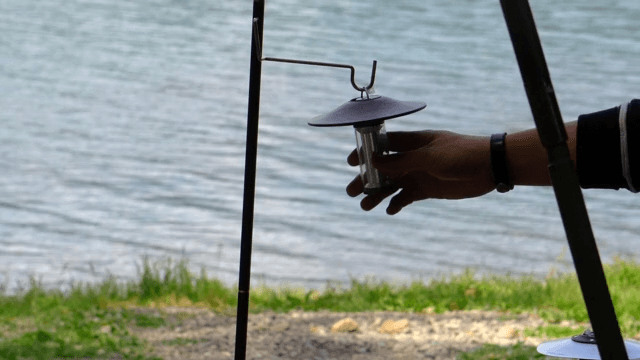 Setting up a camping lantern on the lakeside