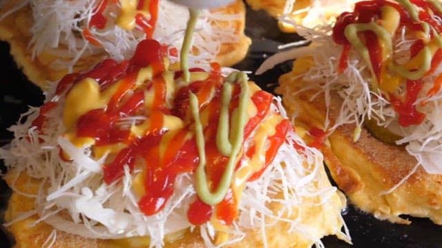 Drizzling sauce over toast topped with cabbage salad