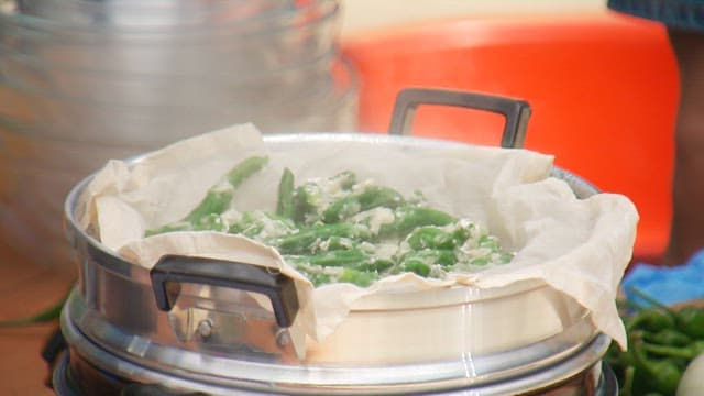 Cooking chili peppers in a steamer with steam rising from the pot