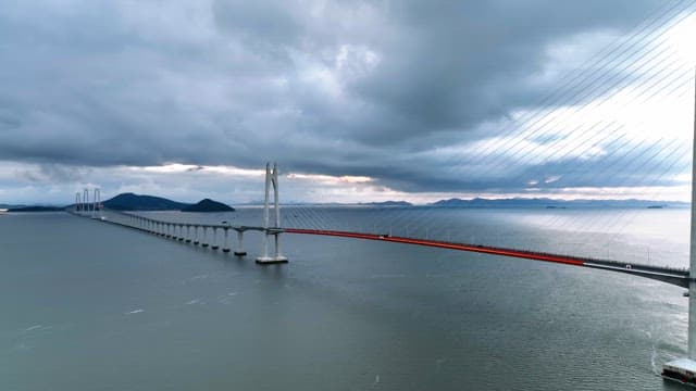 Long bridge over a calm sea under cloudy skies
