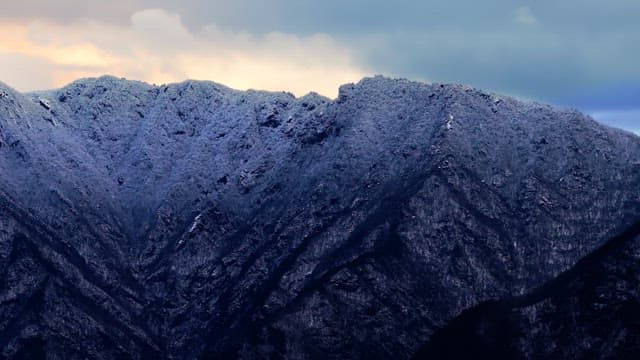 Snow-covered mountains under cloudy skies
