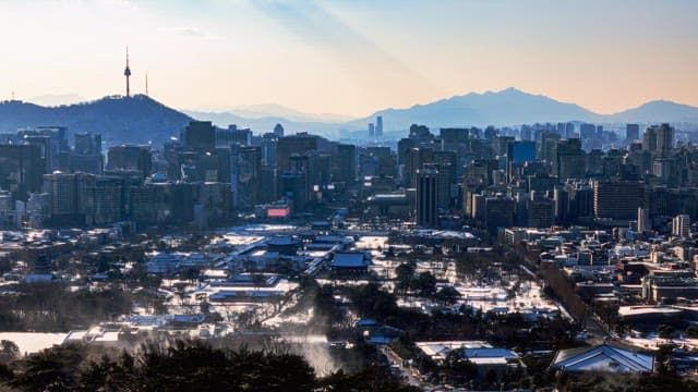View of a bustling cityscape with a mountain in the background on a clear