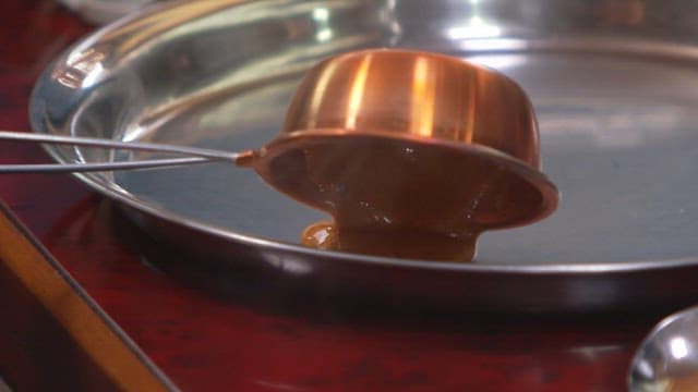 Pouring melted sugar onto a metal tray to make dalgona