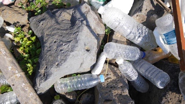 A rocky area filled with plastic waste and debris