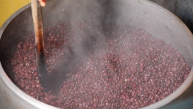 Scene of stirring red beans in a large pot