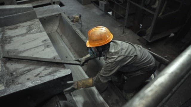 Worker in full safety gear operates machinery in factory
