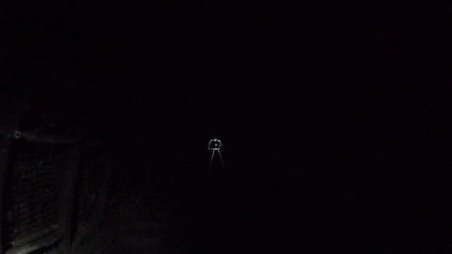 Inside a narrow, dark mine tunnel, illuminated by a flashlight