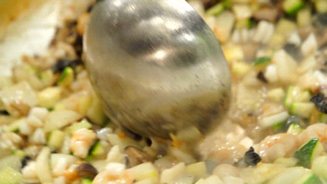 Stir-fried freshwater snail and chopped vegetables in a hot pan