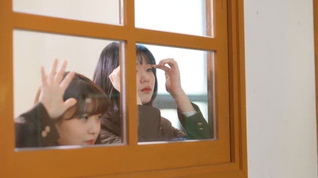 Students looking in through classroom window in hallway