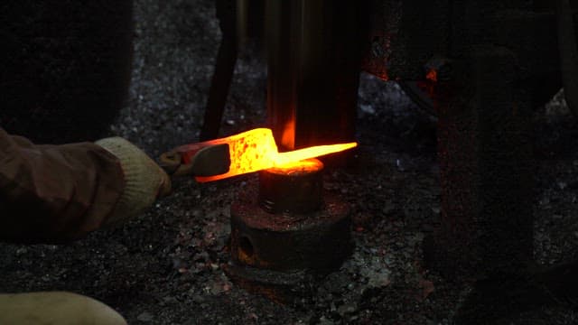 Worker forging metal in a factory