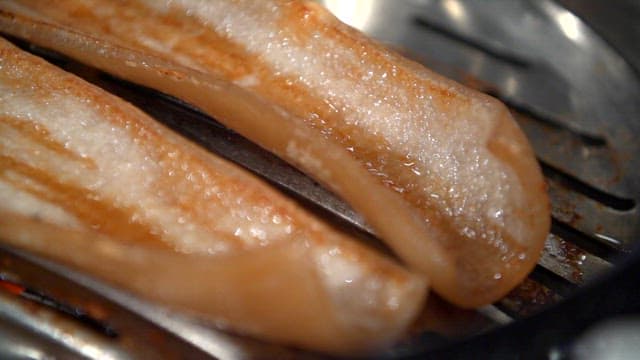 Grilling pork rinds on a metal grill
