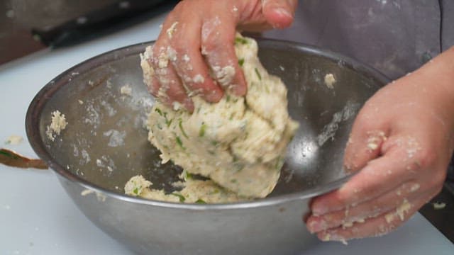 Mixing scone dough made of green onions with hands in a bowl