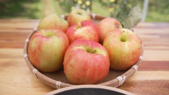 Basket of apples and plate of dessert made with apples and ice cream on wooden table