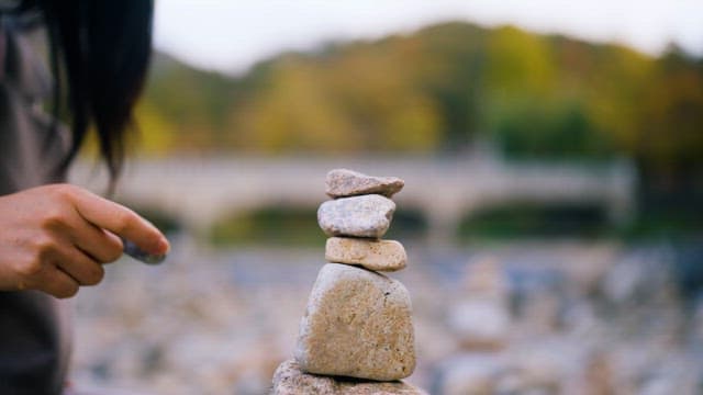 Person arranging stones in balance outdoors