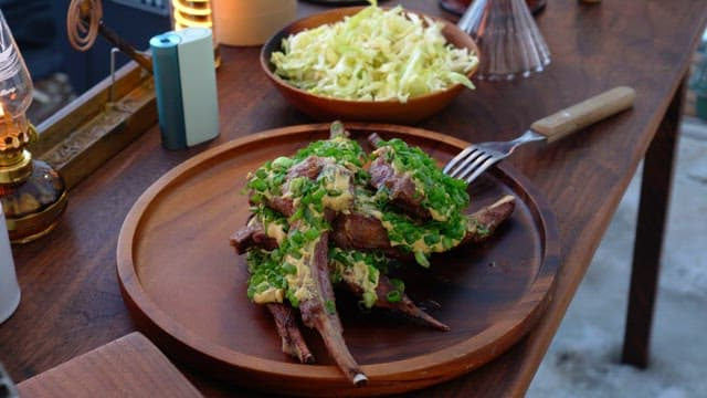 Deliciously prepared dish of lamb chops garnished with spring onions, served with a bowl of shredd