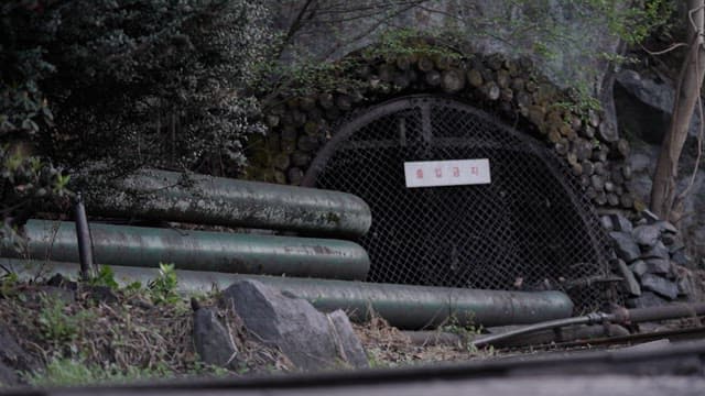 Entrance to an abandoned mine with a no-trespassing sign located in the mountains