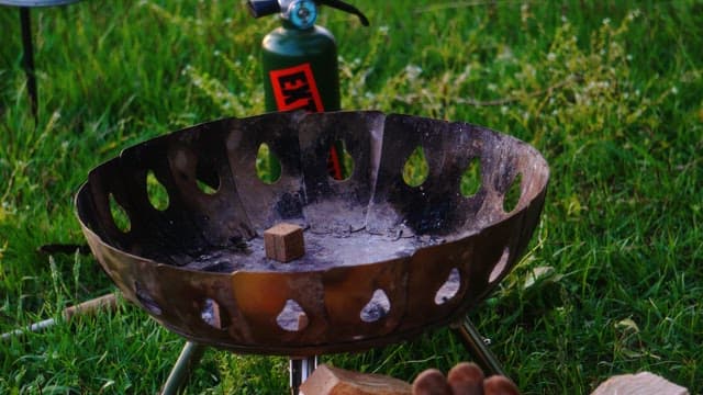 Lighting a fire with a torch on a brazier in the grass