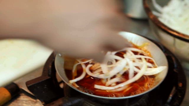 Pork cutlet on top of a pot with boiling onions