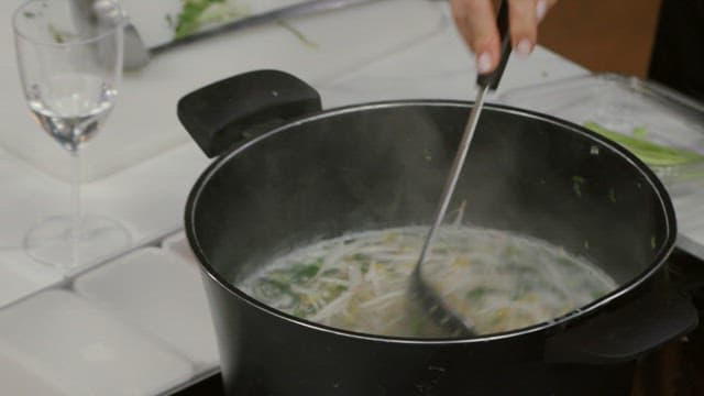 Cooking mussels with bean sprouts in a pot and serving them in a white bowl