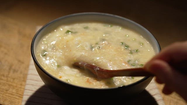 Bowl of warm crab meat porridge with plenty of vegetables and seafood
