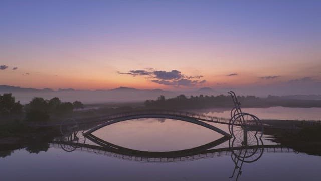 Serene bridge over a misty river at sunset