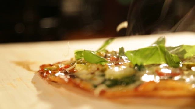 Sprinkling Cheese on a Freshly Baked Pizza