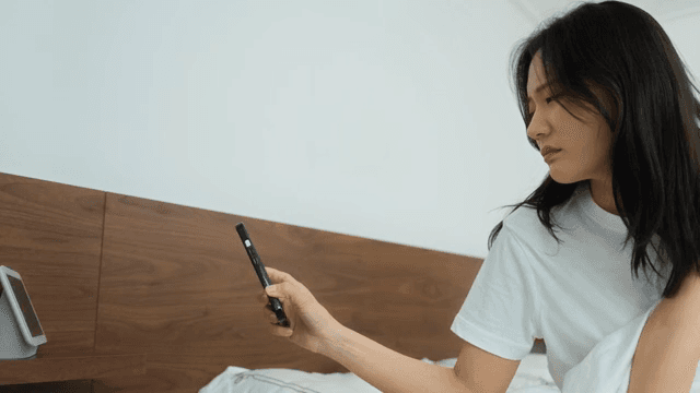 Young Adult Woman Checking Phone in Bed