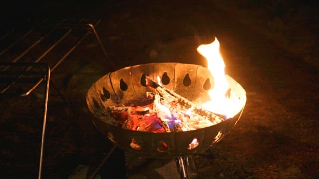 Nighttime outdoor campfire preparation for cooking scene