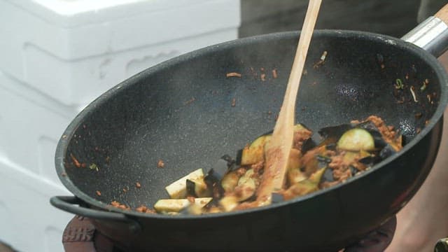 Stir-frying eggplant and minced meat in a wok