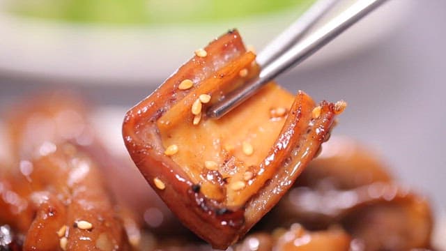 Chopsticks holding glazed seasoned pork intestines