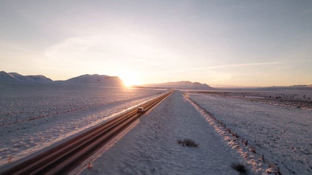Car driving on a snowy road at sunrise