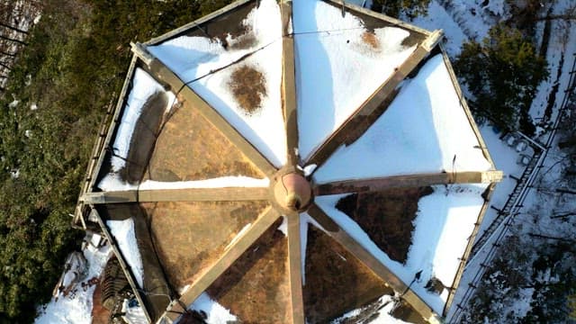 Snow-covered hexagonal structure in a forest