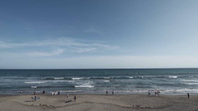 People Playing on a Wide Sandy Beach on a Clear Day