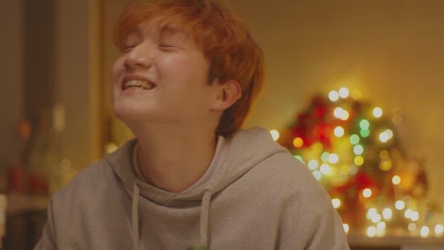 Man smiling happily in a room decorated with Christmas lights