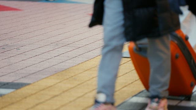 Person walking with an orange suitcase