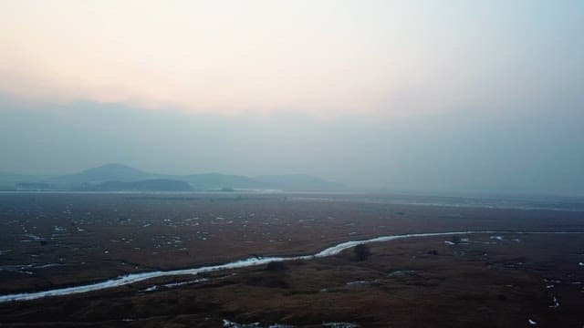 Vast marshland under a hazy sky