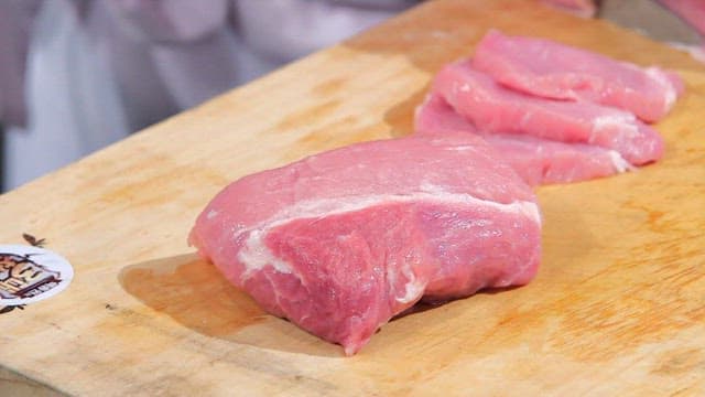 Slicing fresh pork on a wooden board