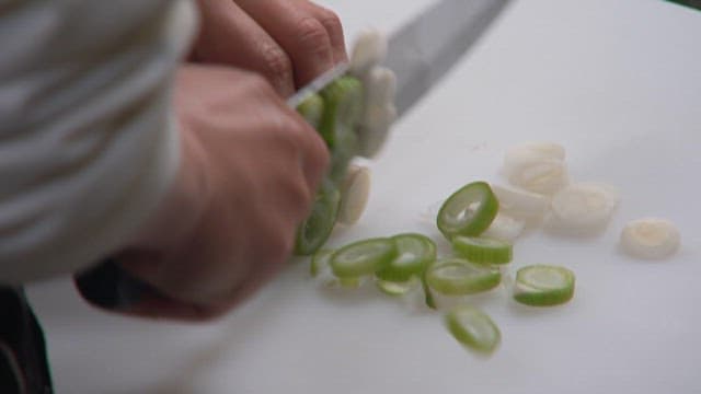 Cutting Green Onions with a Kitchen Knife on a Cutting Board