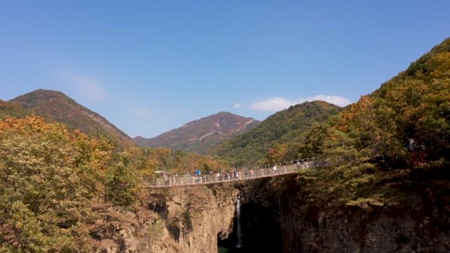 Tourists crossing the suspension bridge in front of the waterfall
