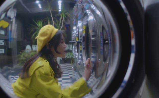 Woman examining washing machine at coin laundromat