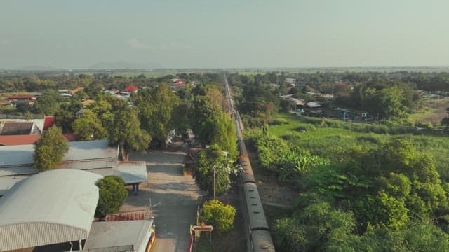 Train Moving through a Residential Area with Surrounding Greenery and Buildings