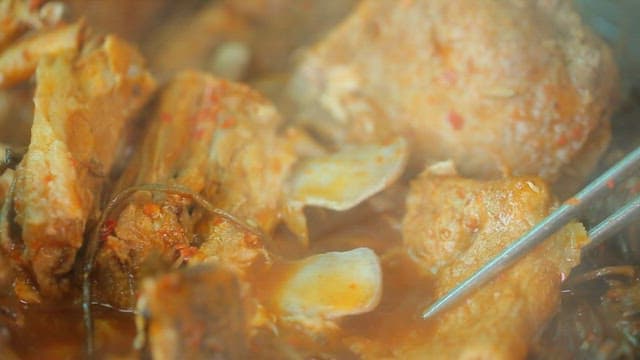 Plate of pork backbone stew meat with sweet potato stem salad picked with chopsticks